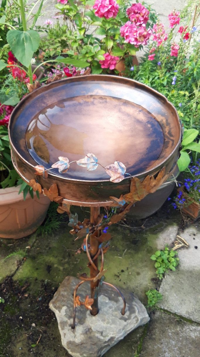 Recycled copper birdbath set in a stone base