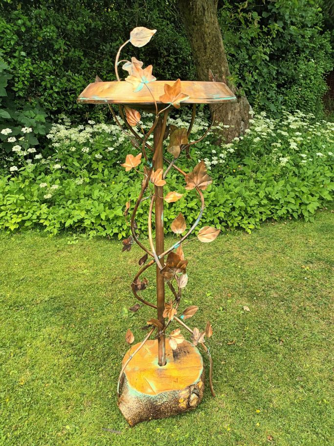 Recycled copper birdbath set in an oak log.